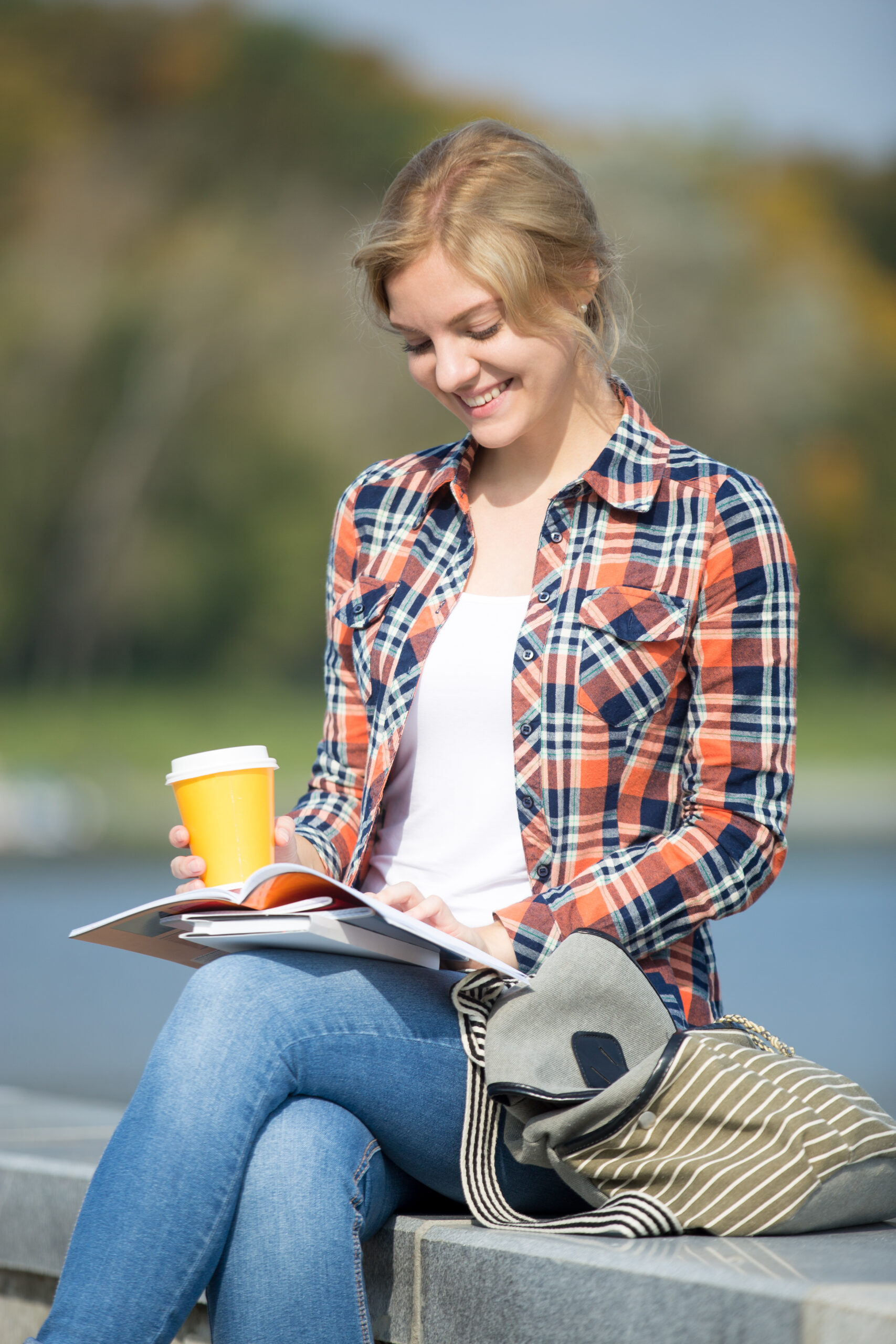 Portrait of a smiling girl sitting at the bridge reading